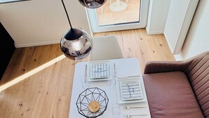 Ein Essbereich mit einem weißen Tisch, gedeckt für vier Personen, mit gestreiften Servietten und einem zentralen Dekorationsobjekt.