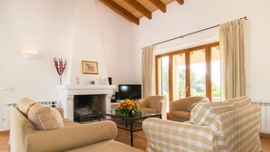 A living room with a fireplace, a television, and two sofas. - Nice home in Arta with private swimming pool, can be inside or outside (Arta)