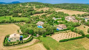 Vista aerea di una zona residenziale con case, campi verdi e una piscina.