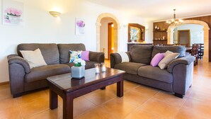 A living room with two sofas, a coffee table, and decorative pillows. There are wall-mounted light fixtures and a chandelier. - Gorgeous home in Arta with private swimming pool, can be inside or outside (Arta)