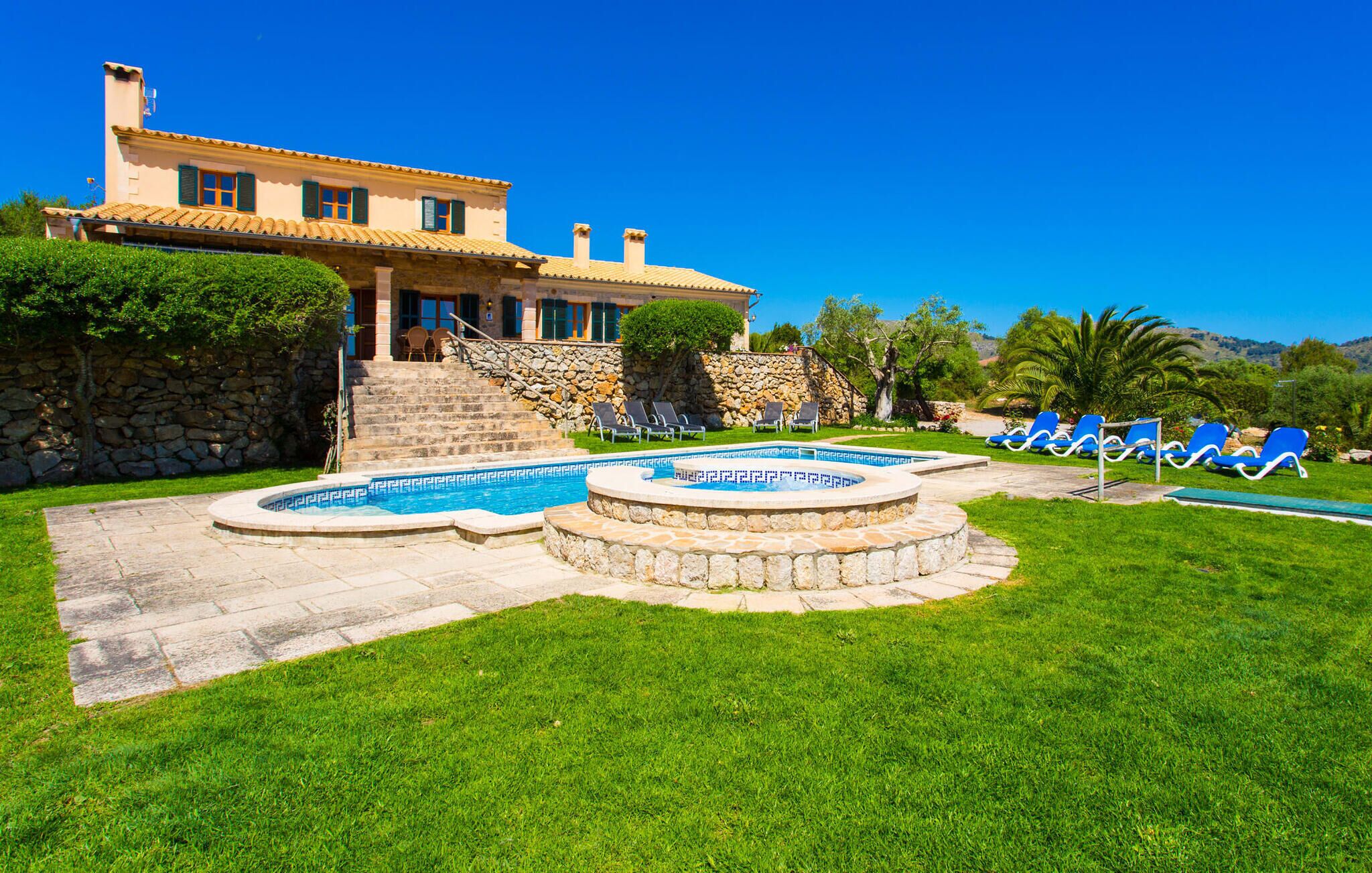 Ein zweistöckiges Haus mit einer Steintreppe, die zu einem Poolbereich führt.