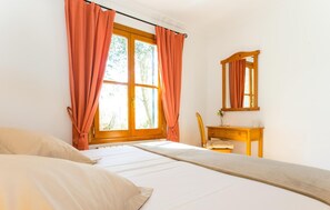 A bedroom with a bed, a wooden nightstand, a mirror, and a window with curtains. - Gorgeous home in Arta with private swimming pool, can be inside or outside (Arta)