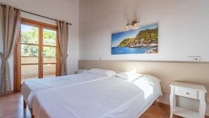 A bedroom with a large bed, a nightstand, a painting of a coastal landscape, and a window with curtains. - Cozy home in Arta with private swimming pool, can be inside or outside (Arta)