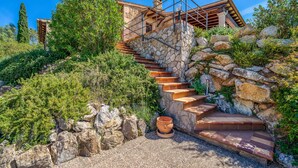 Una escalera de piedra que lleva a una casa de diseño rústico, rodeada de follaje y rocas.