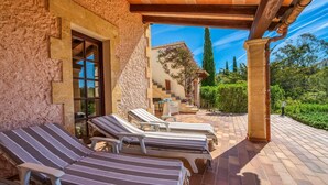 Un espacio al aire libre cubierto con sillones, un muro de piedra y vistas a un jardín.