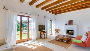 Un ampio soggiorno con camino, televisione e una grande finestra vista giardino.