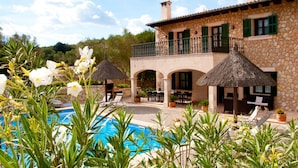 Une villa en pierre dotée d’une piscine, d’un espace salon extérieur et d’un balcon.