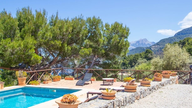 A poolside area with lounge chairs, potted plants, and a view of mountains. - Cozy home in Deia with private swimming pool, can be inside or outside (Deia)