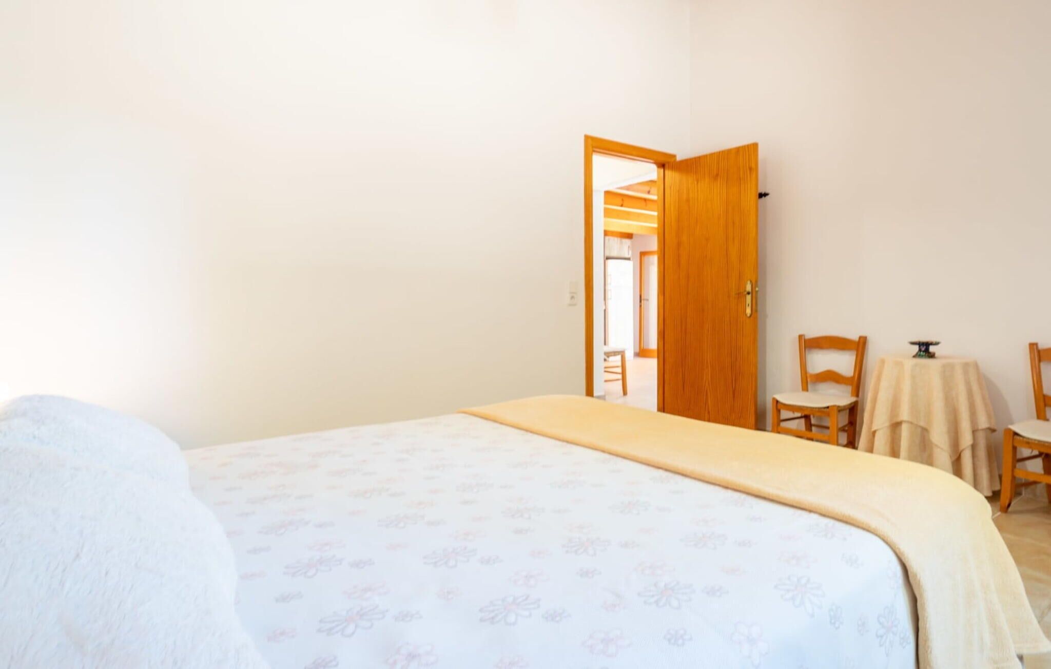 Un dormitorio con una cama, una puerta de madera y una pequeña mesa con sillas.