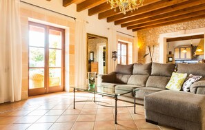 A spacious living room with a glass coffee table, a sofa with multiple cushions, and a stone wall. - Lovely home in Son Carrio with private swimming pool, can be inside or outside (Son Carrio)
