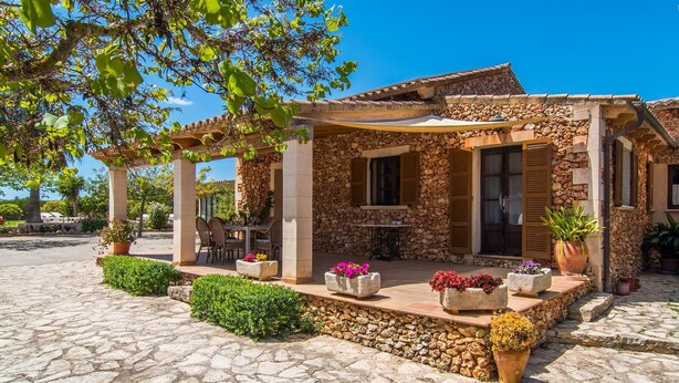 A stone building with a covered patio, stone walls, and potted plants. - 4 bedroom cozy home in Son Servera (Son Servera)