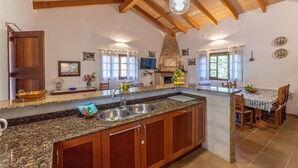 A kitchen with granite countertops, wooden cabinets, a built-in sink, and a brick oven. - 4 bedroom cozy home in Son Servera (Son Servera)