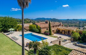 Una villa con piscina, arquitectura de piedra y vistas al campo.