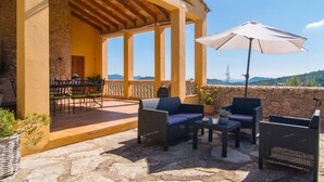 A covered outdoor seating area with stone flooring, a table with chairs, and a large umbrella. - Cozy home in Arta with private swimming pool, can be inside or outside (Arta)