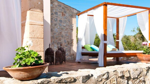 A stone building with a wooden bed structure covered with white fabric. - Luxurious home in Son Servera (Son Servera)