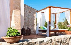 A stone building with a wooden bed structure covered with white fabric. - Luxurious home in Son Servera (Son Servera)