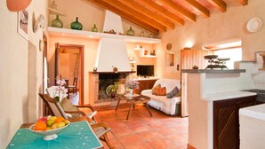 Una sala de estar acogedora con chimenea, un comedor con frutero y una cocina con estufa.