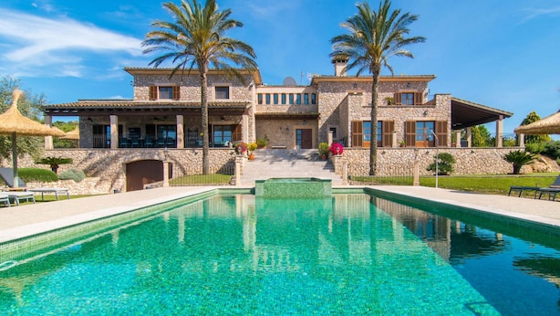 Un grande edificio in pietra con una piscina di fronte.