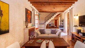 A cozy living room with a wooden ceiling, a sofa, a coffee table, and a staircase leading to a dining area. - Awesome home in Andratx with private swimming pool, can be inside or outside (Andratx)