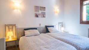 Un dormitorio con dos camas, una mesita de noche con lámpara e iluminación en la pared.
