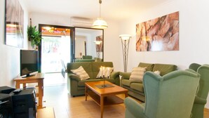Ein modernes Wohnzimmer mit grünen Sofas, einem Holztisch und einem Flachbildfernseher.
