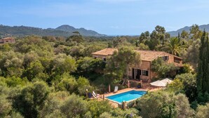 Une villa avec piscine, entourée d’une végétation luxuriante et avec des montagnes en toile de fond.