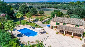 Een villa met een zwembad, terras en uitzicht op het omliggende platteland.