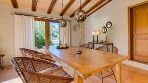 Un coin repas avec une table en bois, des chaises en osier et des lampes suspendues.