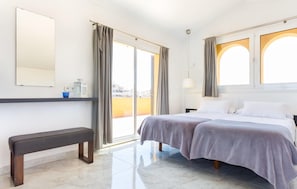 A hotel room with a bed, bench, and a large window with curtains. - Cozy home in Cala Millor with private swimming pool, can be inside or outside (Cala Millor)