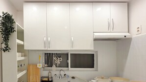 Cocina compacta con armarios blancos, un fregadero, un microondas y una lavadora integrada.