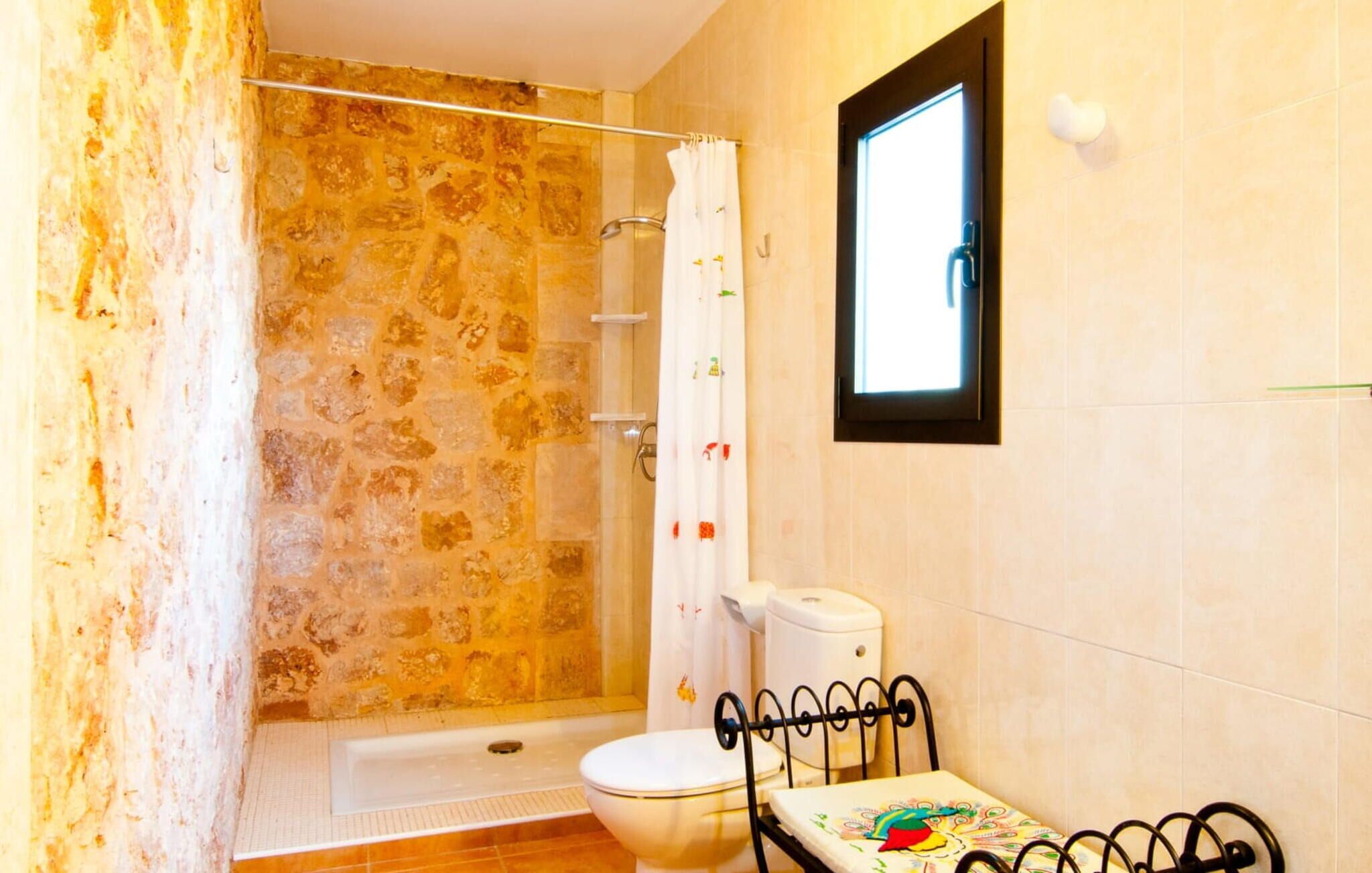 Un baño con ducha, inodoro y una pequeña mesa con un tapete colorido.