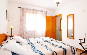 A bedroom with a bed, a nightstand, a lamp, a mirror, and a door. - Beautiful home in Can Picafort (Can Picafort)