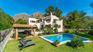 Eine moderne Villa mit Swimmingpool, Sitzgelegenheiten im Freien und Blick auf die Berge.