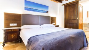 A bedroom with a bed, nightstands, a wooden wardrobe, a painting of a beach, and a door. - Lovely home in Cala Millor with private swimming pool, can be inside or outside (Cala Millor)