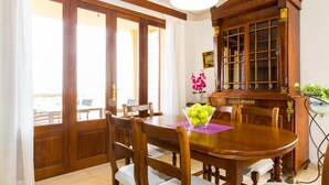 A dining area with a wooden table, chairs, and a cabinet with glass doors. - Lovely home in Cala Millor with private swimming pool, can be inside or outside (Cala Millor)