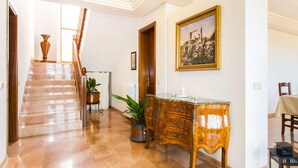 A hallway with a marble staircase, wooden furniture, and a painting on the wall. - Lovely home in Cala Millor with private swimming pool, can be inside or outside (Cala Millor)