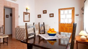 A dining area with a wooden table, chairs, a bowl of oranges, and framed pictures on the wall. - Lovely home in Colonia de Sant Jordi (Colonia de Sant Jordi)