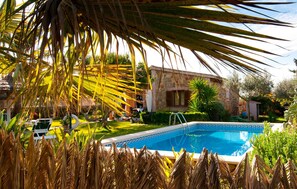 Una piscina circondata da palme e un edificio in pietra.