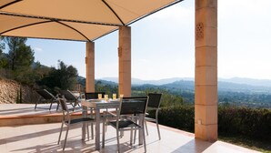 An outdoor patio with a table and chairs, a large umbrella, and a scenic view of the countryside. - Luxurious home in Manacor with private swimming pool, can be inside or outside (Manacor)