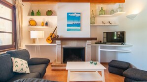 Een woonkamer met een open haard, een televisie en een gitaar.
