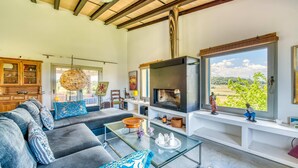 Una sala de estar moderna con un sofá, una mesa de centro de vidrio, una chimenea y vistas a zonas verdes.
