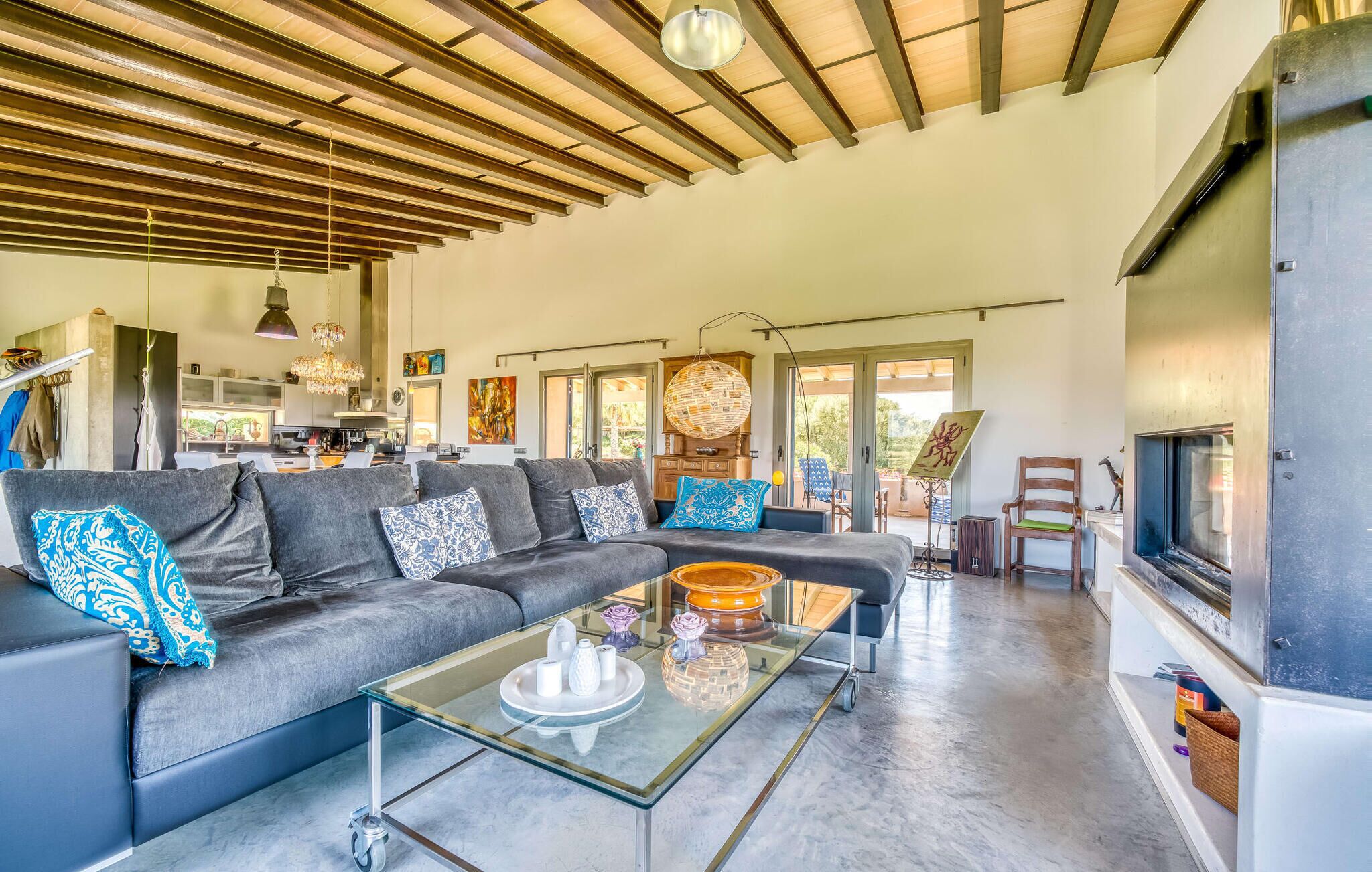 A modern living room with a sectional sofa, a glass coffee table, and a fireplace.