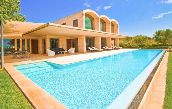A modern poolside area with a clear blue pool, lounge chairs, and a covered seating area with a table and chairs. - Amazing home in Felanitx with private swimming pool, can be inside or outside (Felanitx)