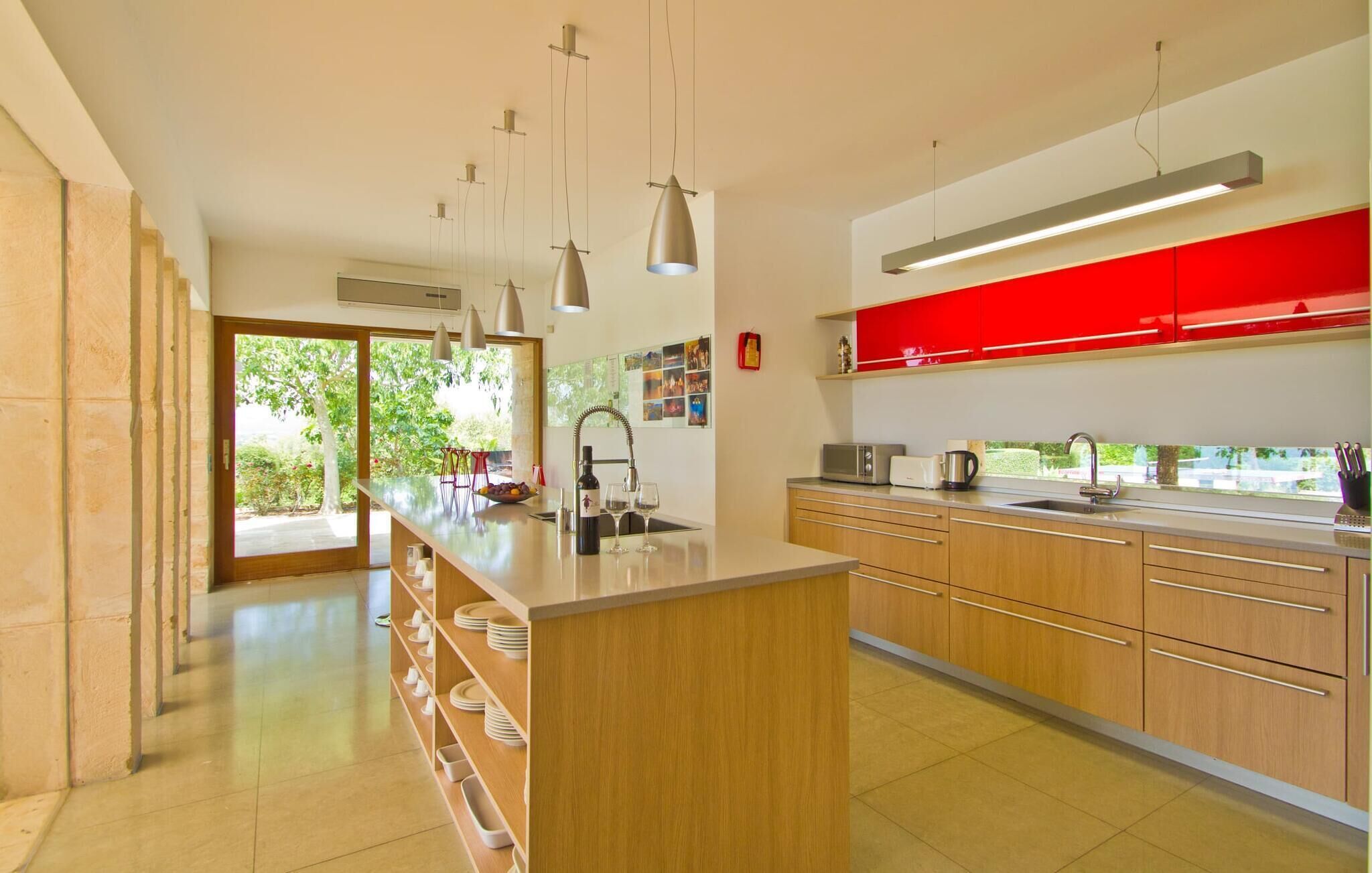 Une cuisine moderne avec un îlot central, des armoires en bois et un mur d’accent rouge.