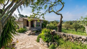 A rustic stone house with a stone pathway leading to the entrance, surrounded by lush greenery and a stone wall. - Lovely home in Arta with private swimming pool, can be inside or outside (Arta)