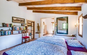 Une chambre à coucher avec un grand lit, une bibliothèque, une chaise en bois et un miroir.