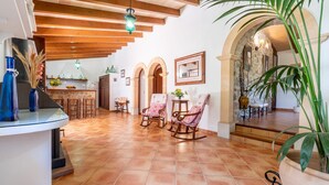 A spacious living area with a tiled floor, wooden furniture, and a stone wall. - Nice home in Arta with private swimming pool, can be inside or outside (Arta)