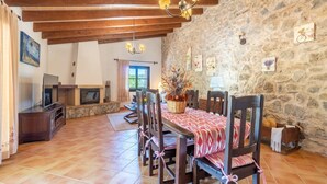 A dining area with a stone wall, wooden ceiling beams, and a fireplace. - Nice home in Arta with private swimming pool, can be inside or outside (Arta)