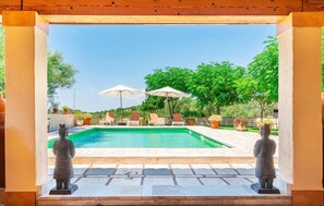 A swimming pool with lounge chairs and umbrellas, surrounded by greenery and statues. - Amazing home in Son Macia with private swimming pool, can be inside or outside (Son Macia)