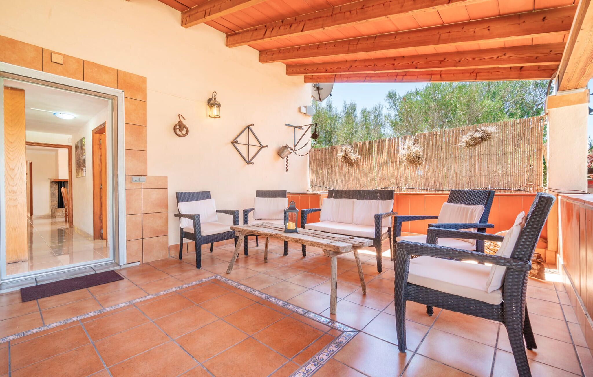 A patio area with wicker furniture, a wooden table, and a view of the outdoors.